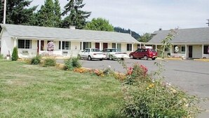 A motel with a single-story structure, a covered parking area, and a small garden with flowers. - Valley Inn (Lebanon)