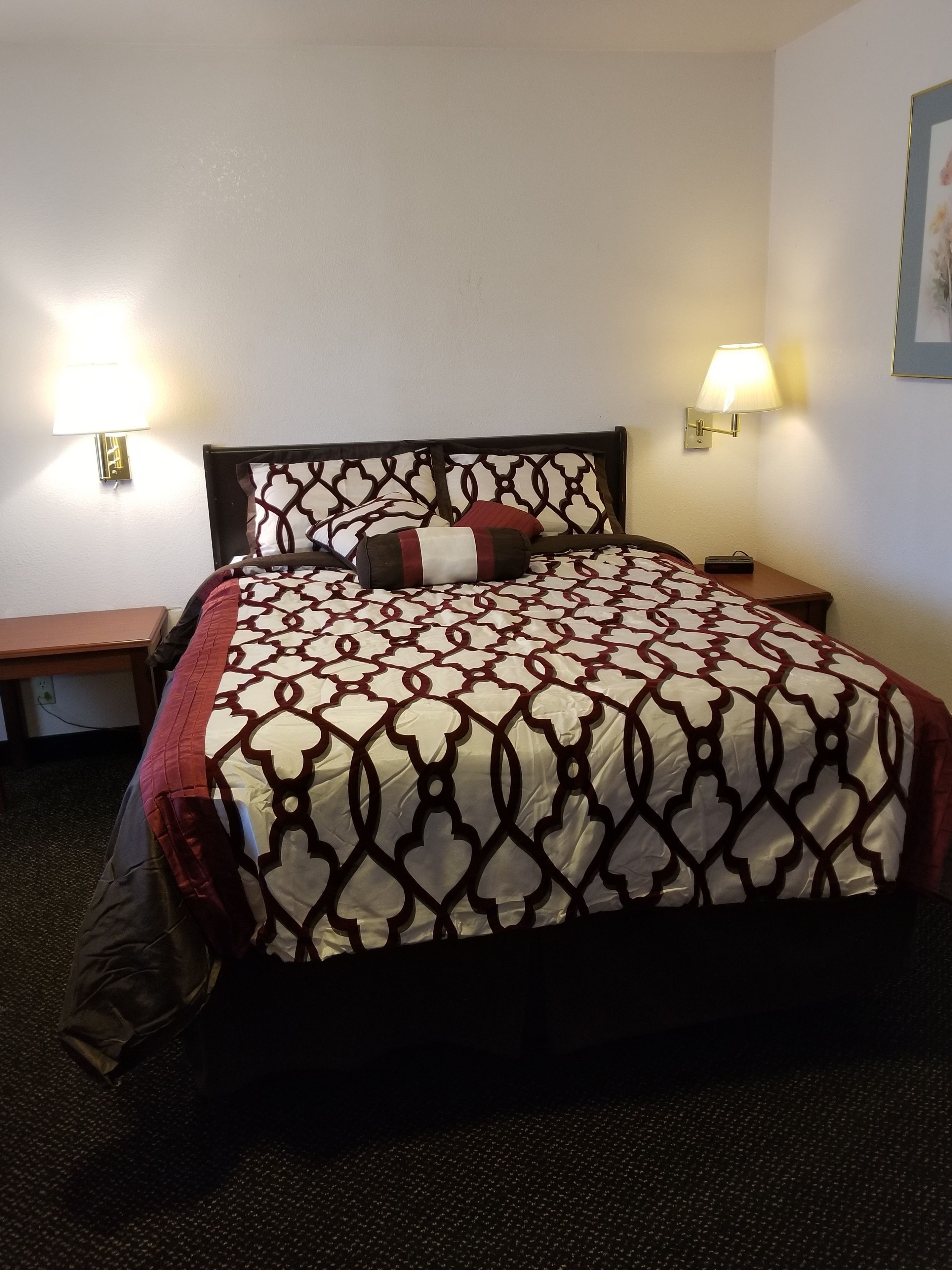 Een hotelkamer met een bed, twee nachtkastjes en twee wandlampen.