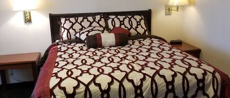 A hotel room with a bed, two bedside tables, and two wall-mounted lamps.