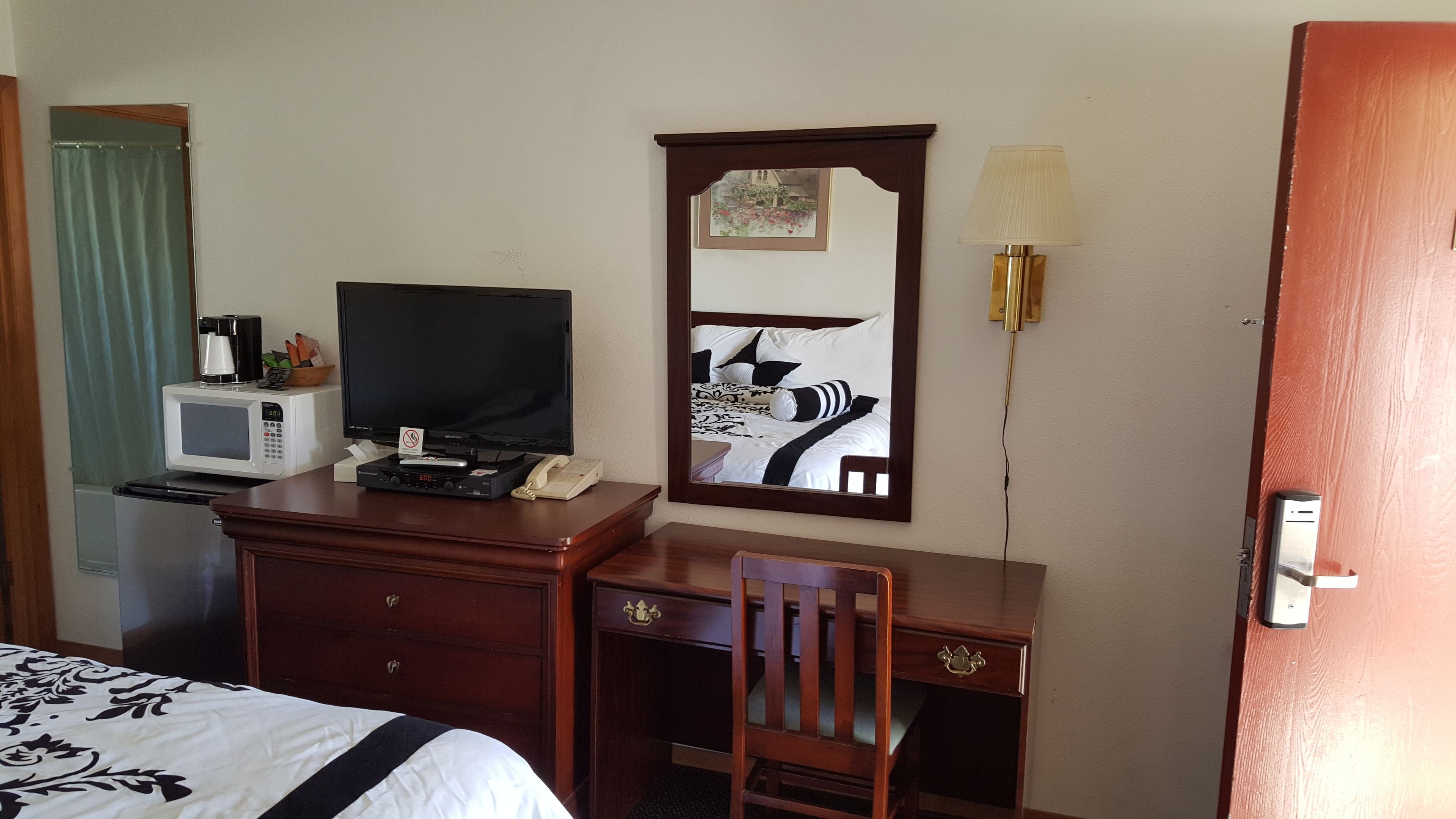 A hotel room with a bed, a desk with a telephone, a microwave, and a television.