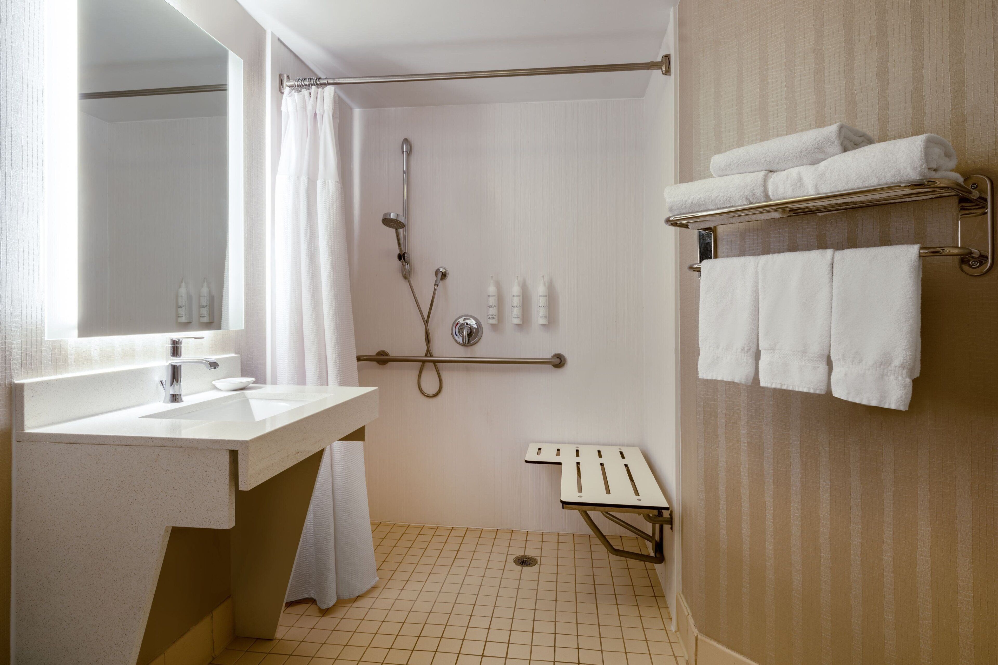 A modern bathroom with a sink, mirror, shower, and towel rack.