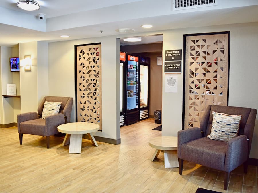 A lobby with two armchairs, a small round table, and a vending machine.