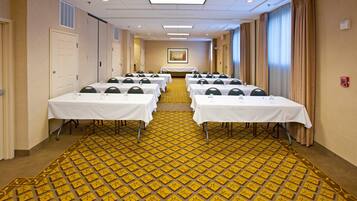 A conference room with multiple tables, chairs, and a patterned carpet.