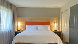 Una habitación de hotel con una cama grande, dos mesitas de noche con lámparas, un teléfono y una puerta.