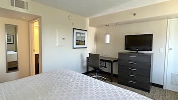 Una habitación de hotel con cama, escritorio, silla, televisor y armario.