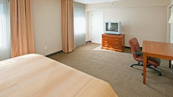 A hotel room with a large bed, a wooden dresser, a television, and a desk.