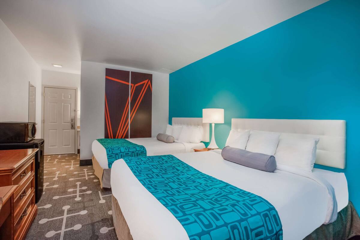 Ein Hotelzimmer mit zwei Betten, einem Fernseher und einem großen Fenster.