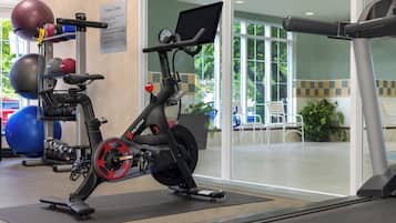 Un gimnasio con una bicicleta estática, una cinta de correr y varias pelotas de ejercicio.