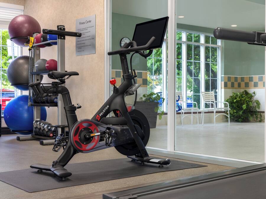 Ein Fitnessstudio mit einem Ergometer, Laufband und verschiedenen Trainingsbällen.