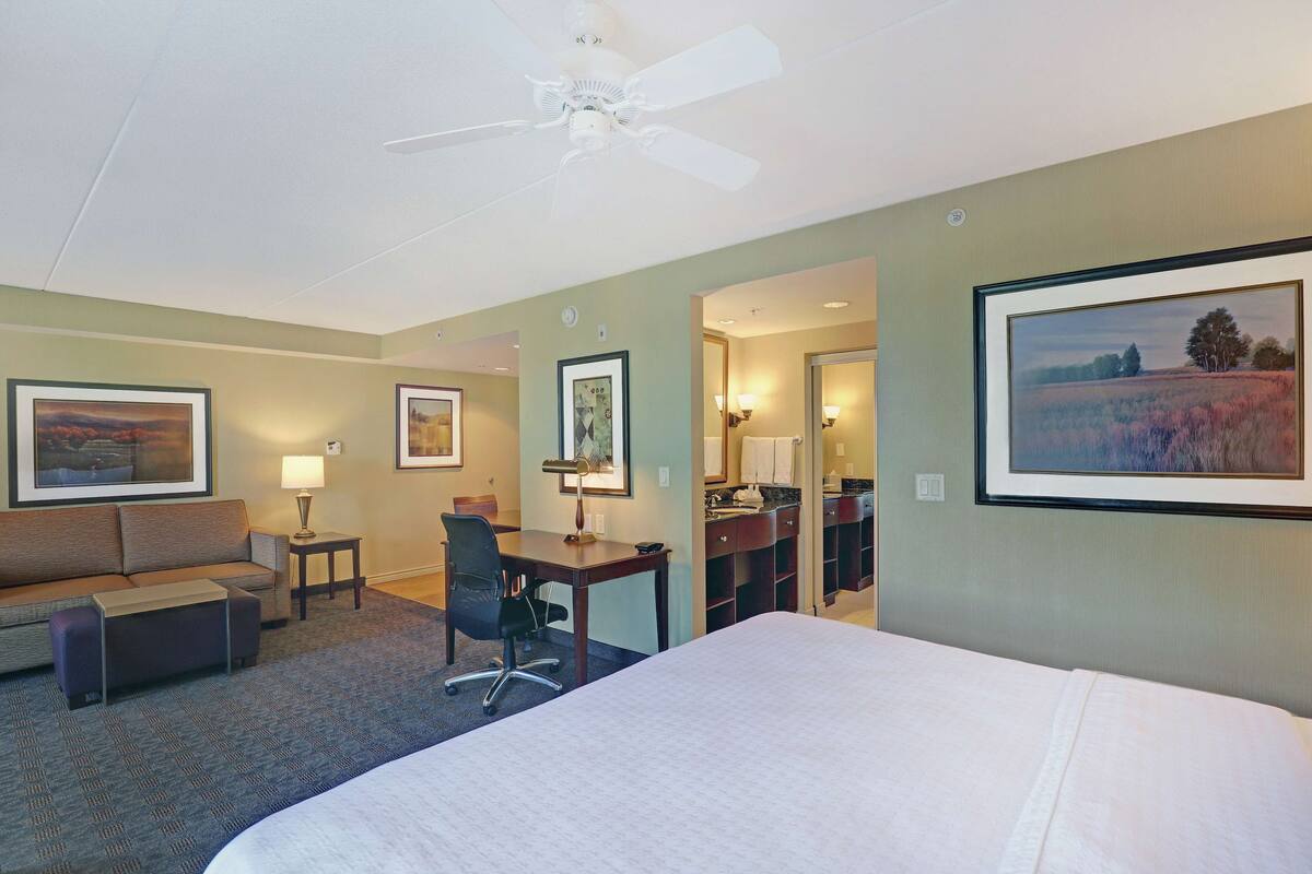 Une chambre d’hôtel équipée d’un lit, d’un bureau, d’une chaise, d’un canapé et d’un ventilateur de plafond.