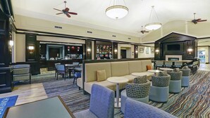 Eine Hotelhalle mit Sitzgelegenheiten, einer Bar und einem Fernseher.