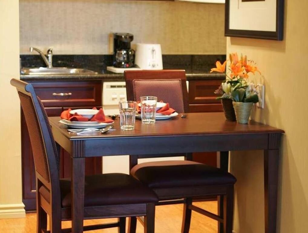 A dining table set with plates, glasses, and a vase of flowers.