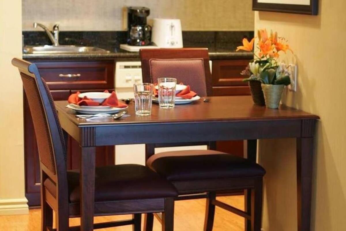 Une table à manger dressée avec des assiettes, des verres et un vase de fleurs.