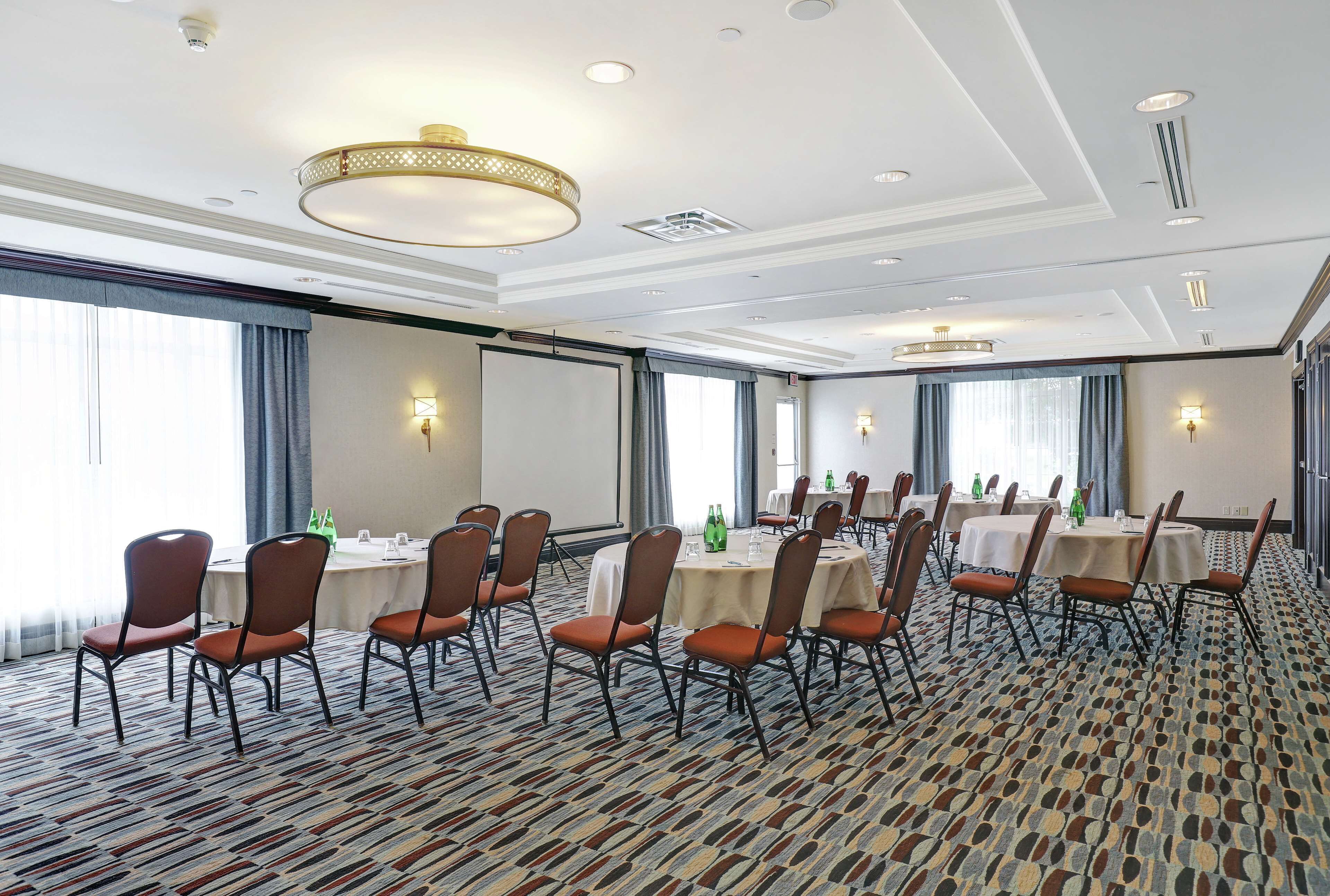 A conference room with round tables, chairs, and a patterned carpet.