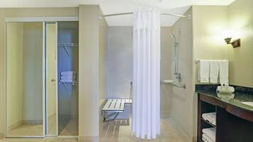 Un baño moderno con cabina de ducha de vidrio, cortina de ducha blanca, tocador con lavamanos y un perchero para toallas.