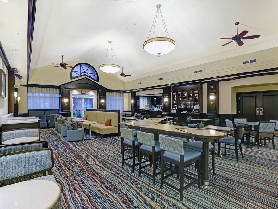 A hotel lobby with a patterned carpet, seating areas, and a bar.