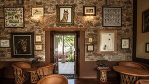 Una habitación con piso de madera, sillas de cuero y pared de piedra decorada con cuadros.