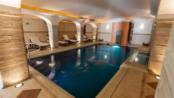 An indoor swimming pool with lounge chairs and stone walls.