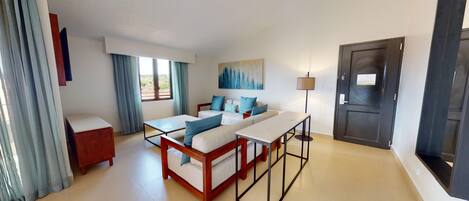 A hotel room with a bed, a desk, a chair, a lamp, and a door.