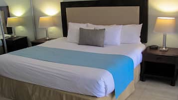 Una cama bien tendida con una colcha azul y blanca, dos lámparas de noche y un cabecero de madera oscura.