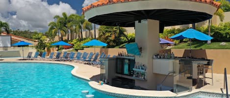 A pool area with a bar and lounge chairs.