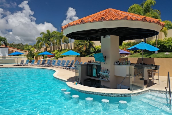 A pool area with a bar and lounge chairs.