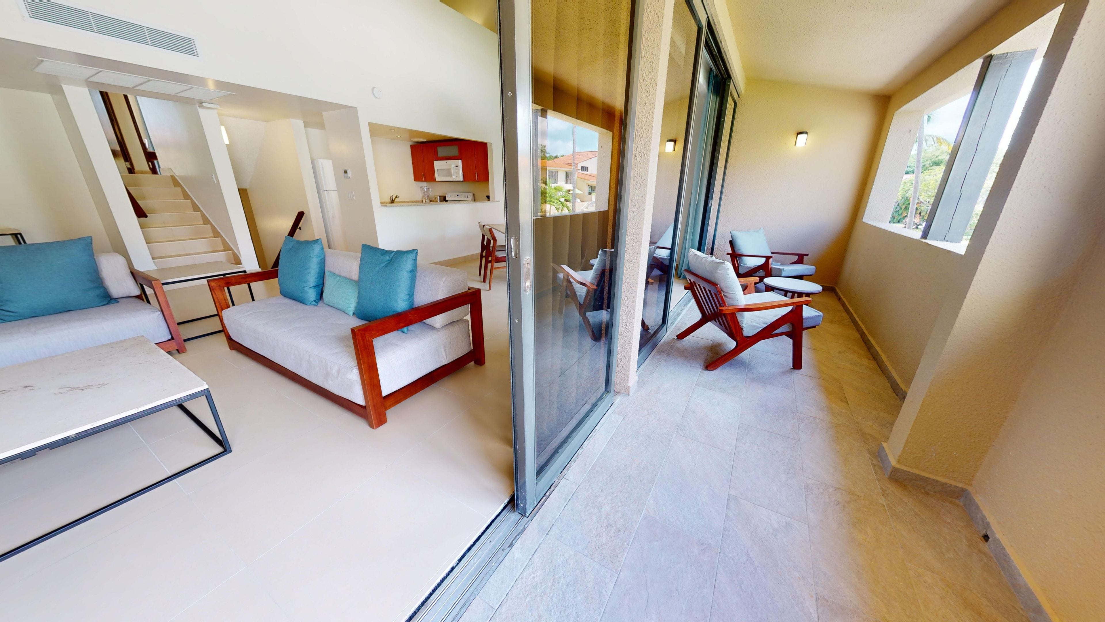 A modern living room with a sofa, chairs, a table, and a glass partition.
