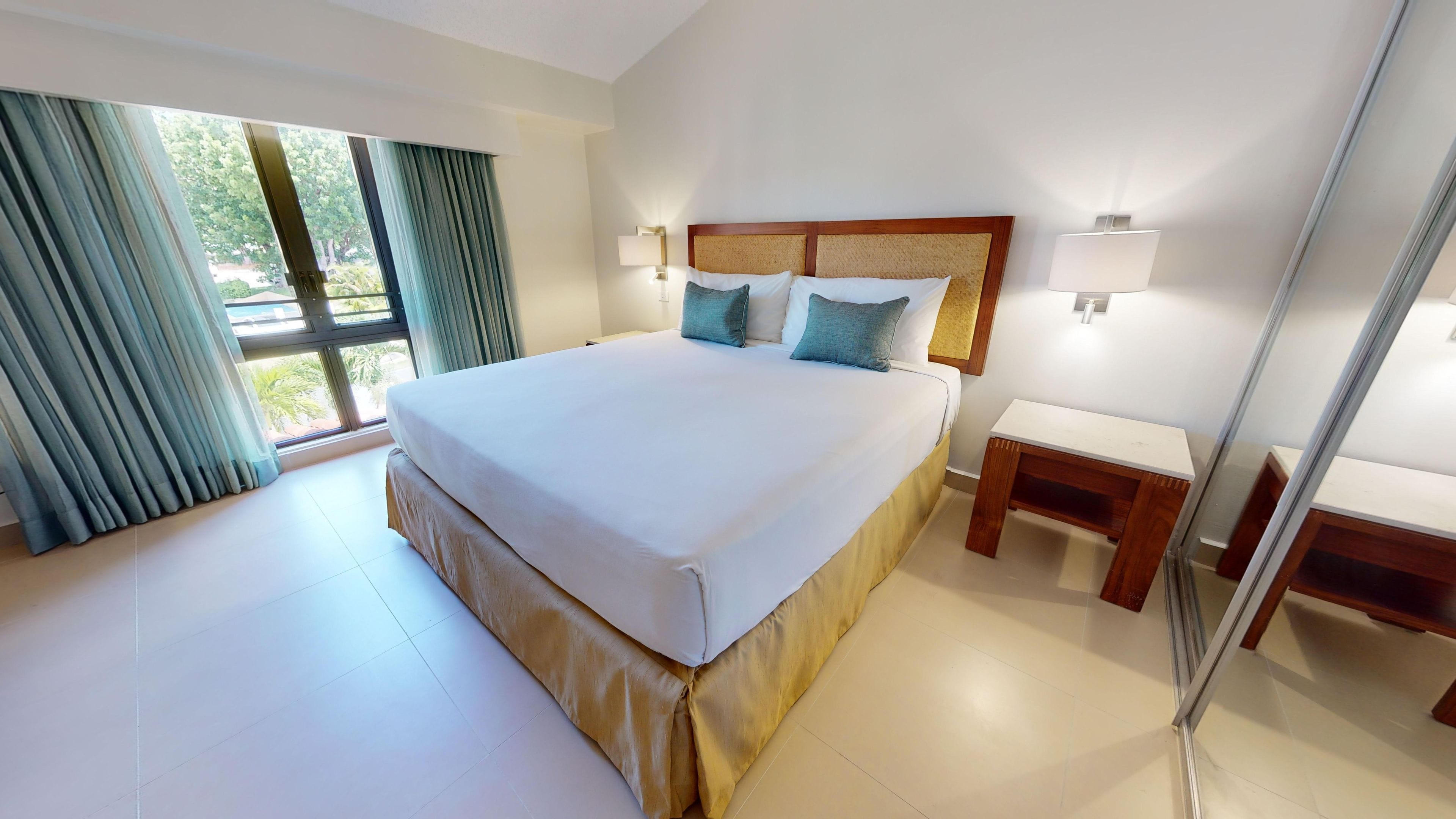 Una habitación de hotel con una cama grande, mesitas de noche y vistas al exterior.