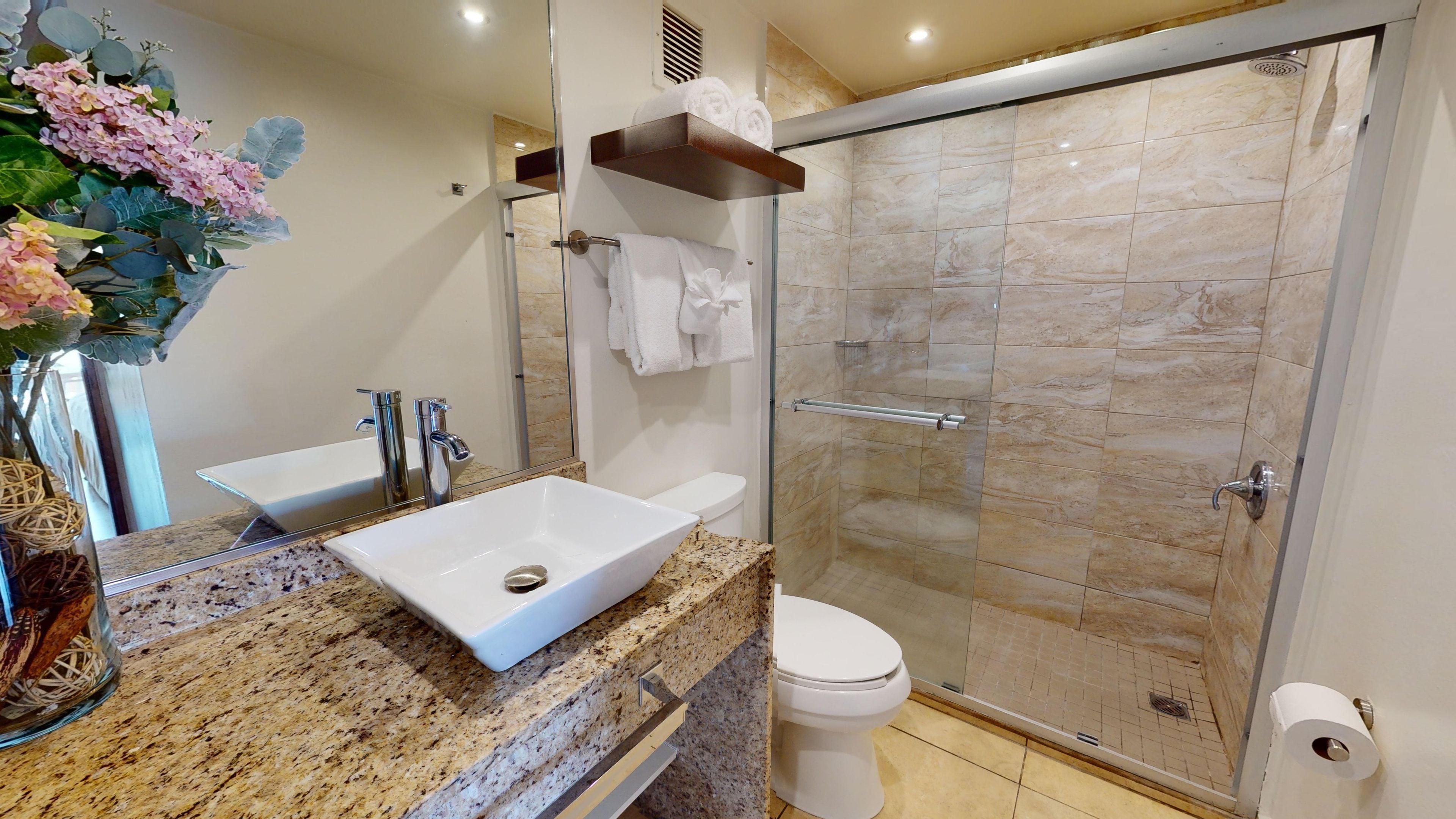 Un baño con ducha de vidrio, lavamanos e inodoro.