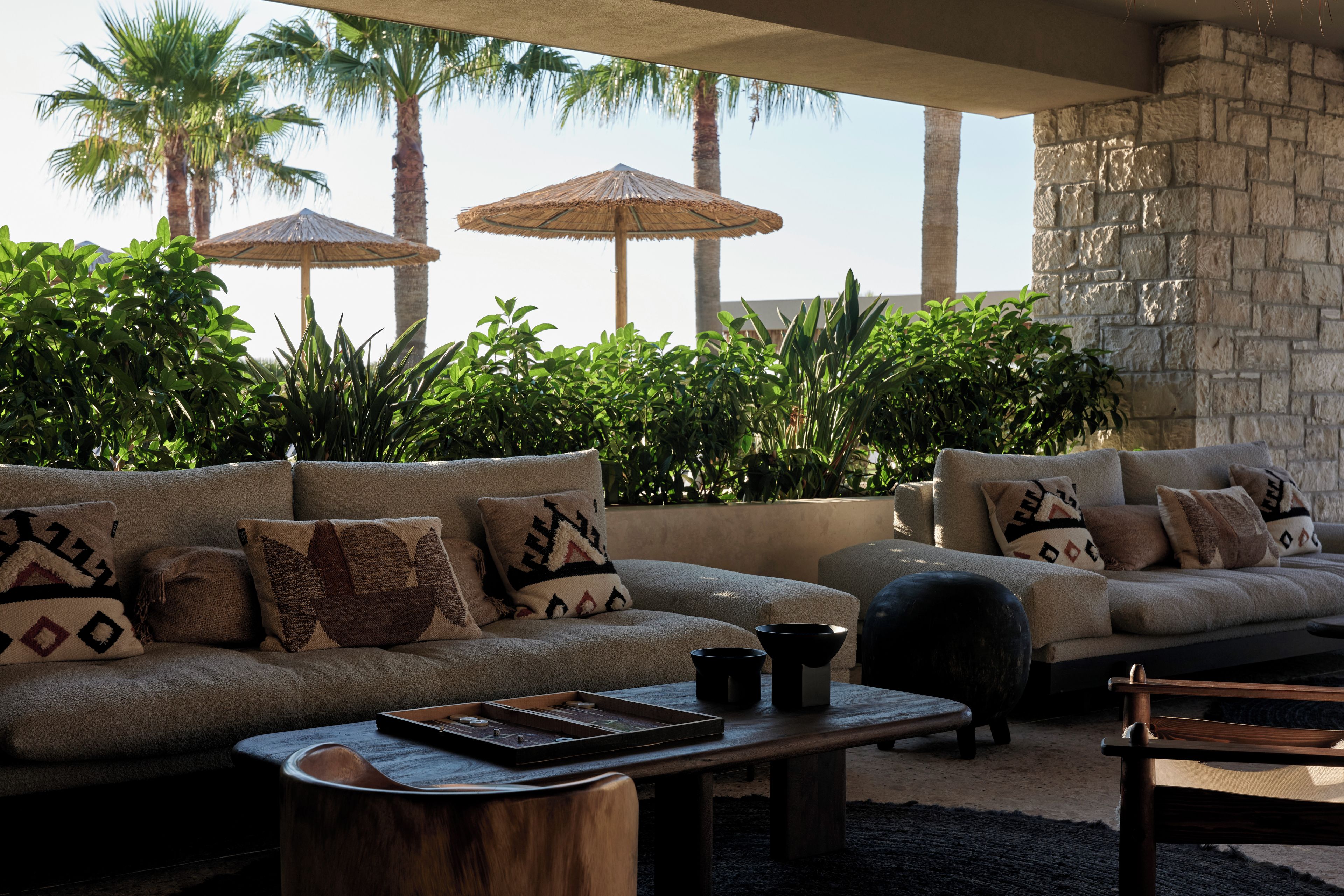 A lounge area with two sofas, a coffee table, and a stone wall.