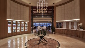 A spacious lobby with a central glass table surrounded by white orchids, flanked by wooden paneling and glass display cases. - Atlantica Kalliston Resort - Adults Only (Chania)