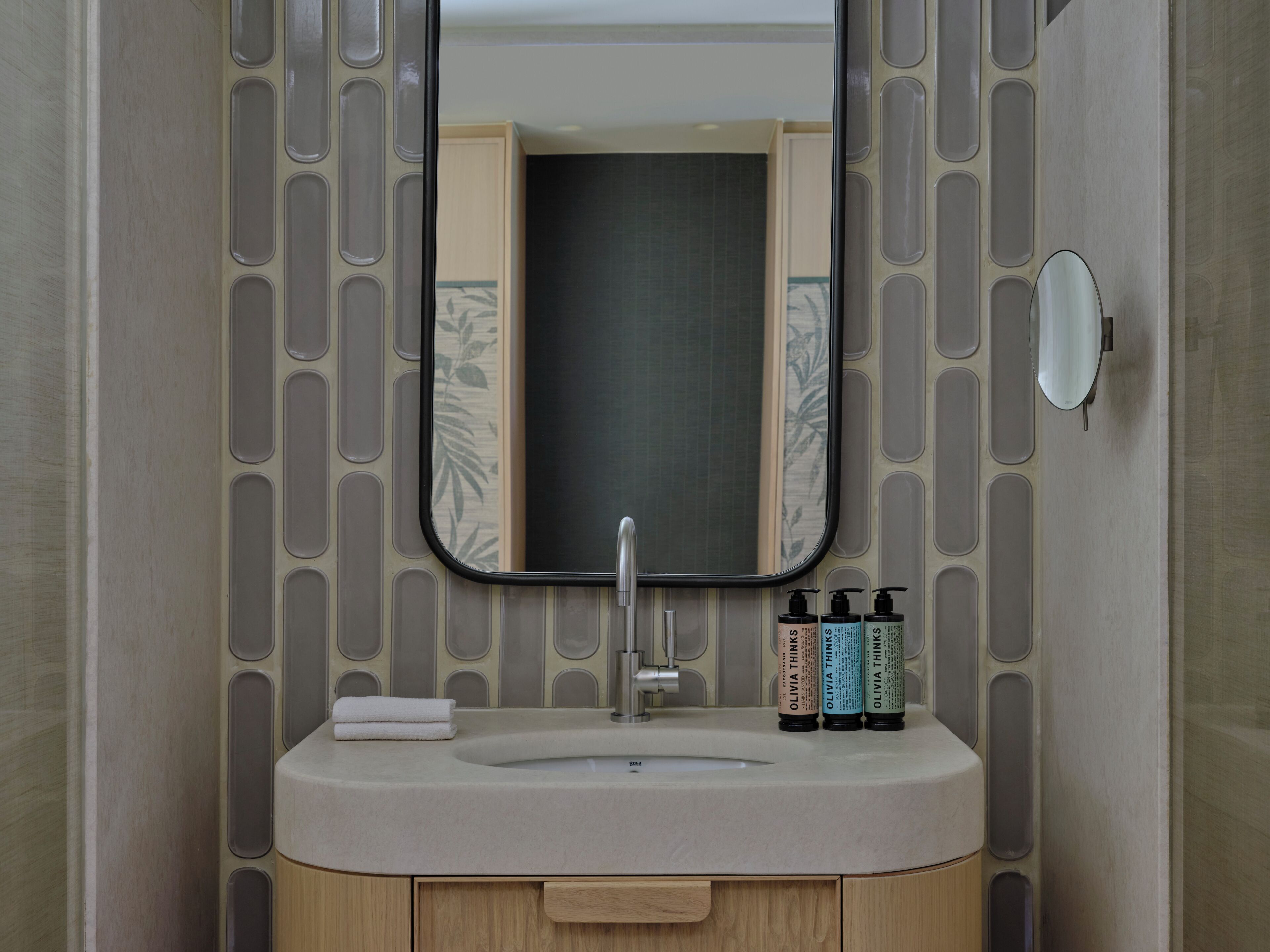 Un baño con lavamanos, espejo y artículos de aseo.