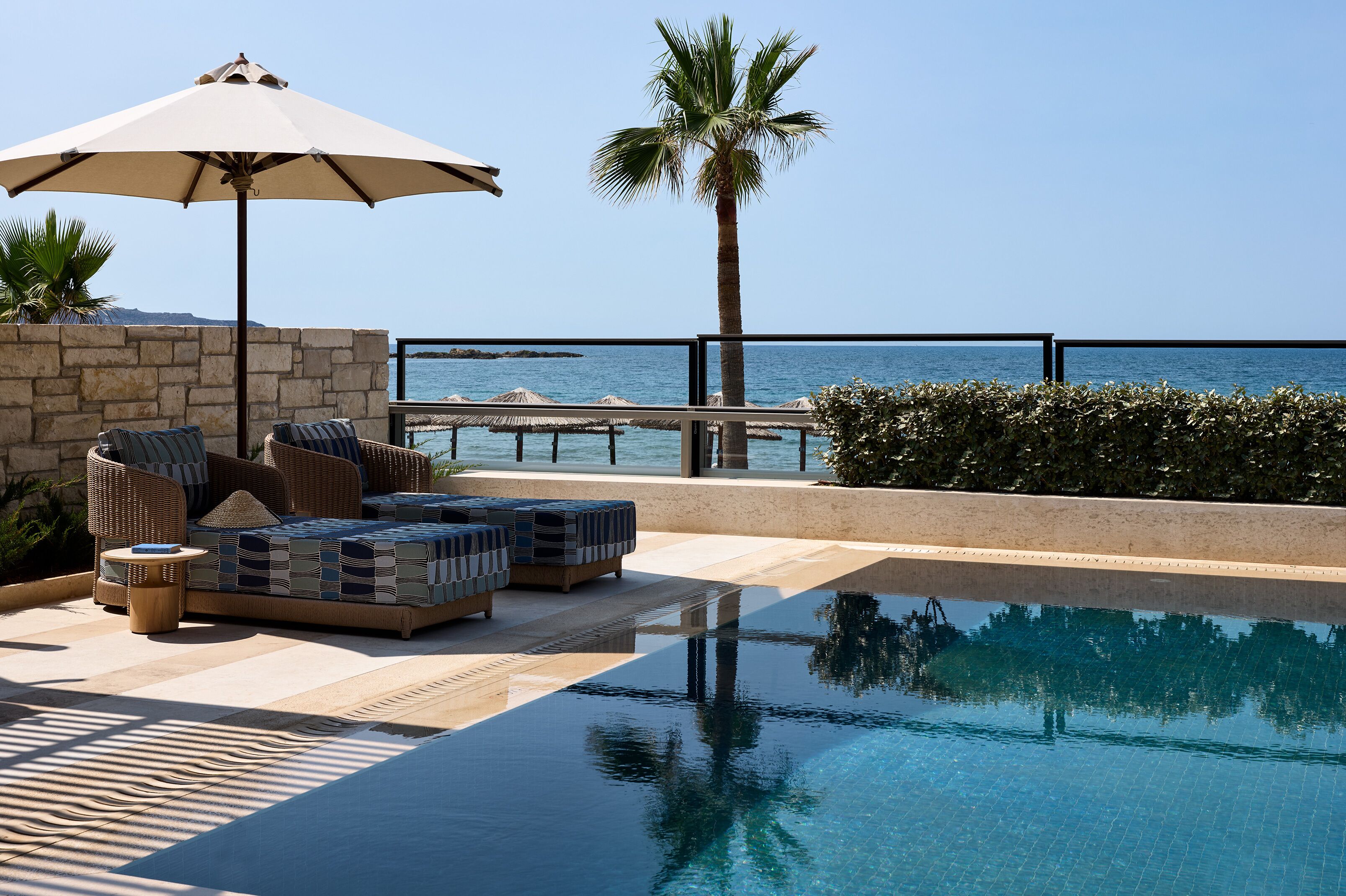 Uma área de piscina com espreguiçadeiras, uma mesa e um guarda-sol.