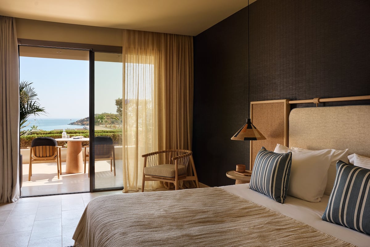 Habitación de hotel con una cama grande, una silla, una mesa y vistas al océano.