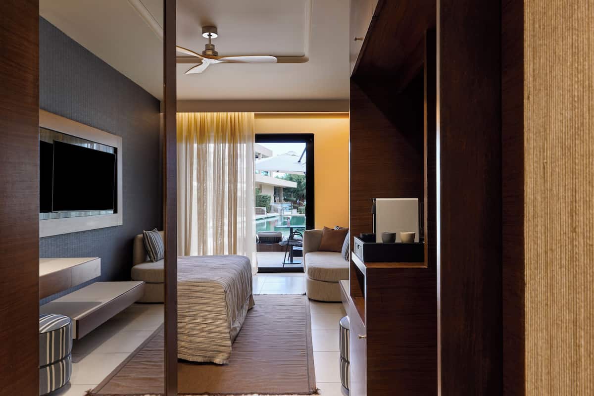 Habitación de hotel moderna con televisión de pantalla plana, sofá, cama, escritorio y vistas al exterior.