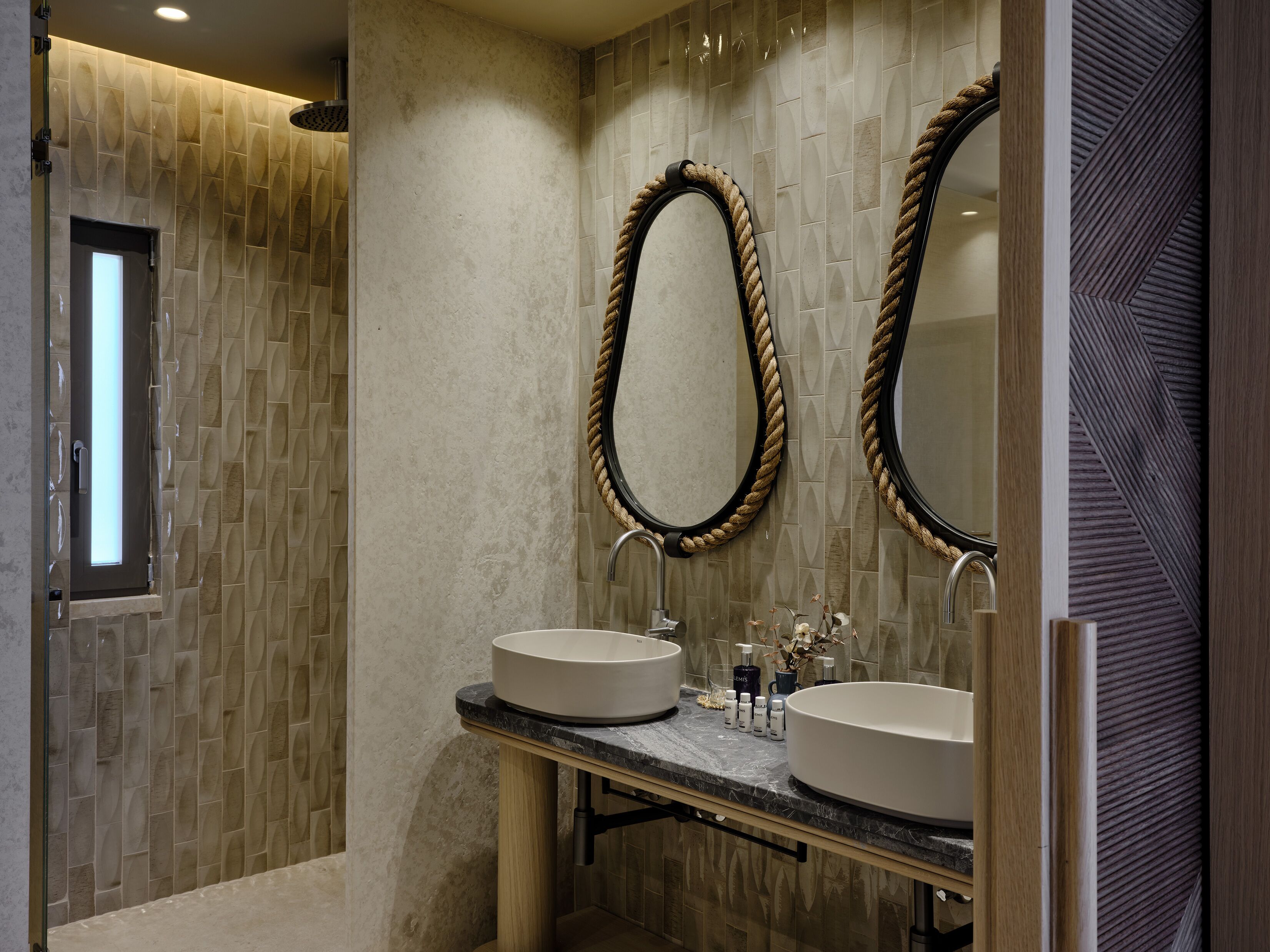Un baño moderno con dos lavamanos, un espejo grande con marco de cuerda y una ventana.