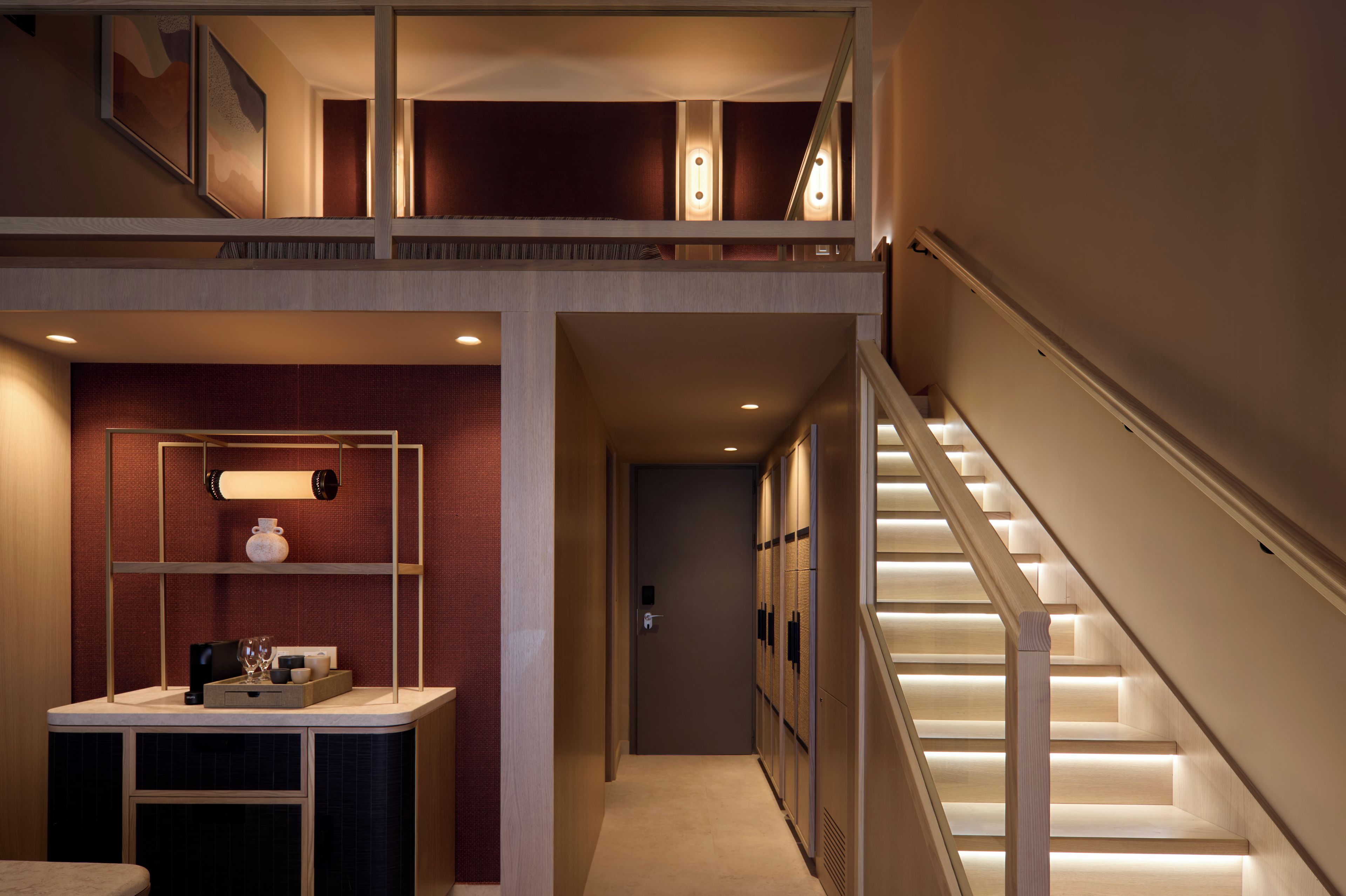 A multi-level interior with a staircase, a hallway leading to a door, and a counter with items on it.