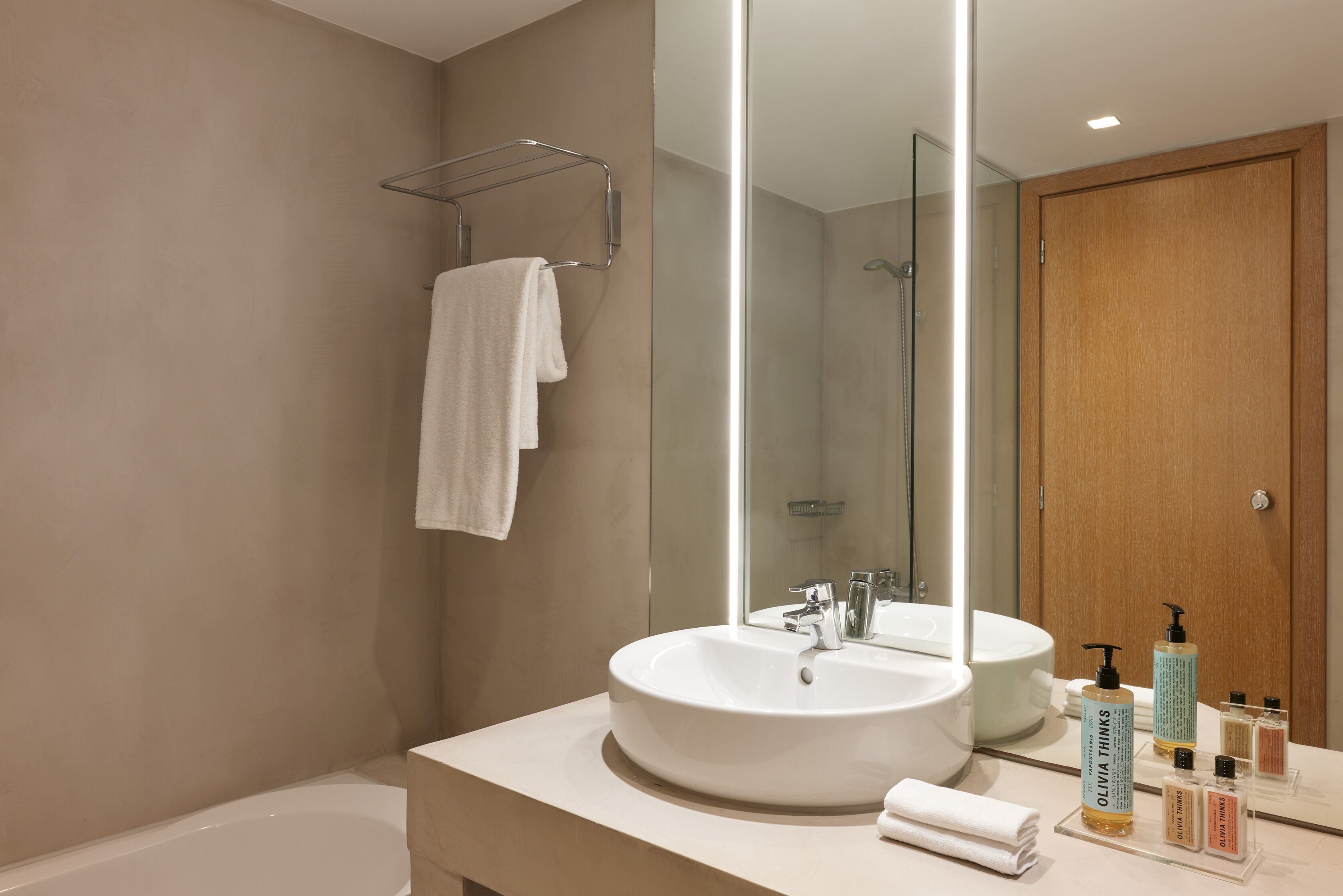 Une salle de bain moderne avec un grand miroir, un lavabo blanc et une baignoire.