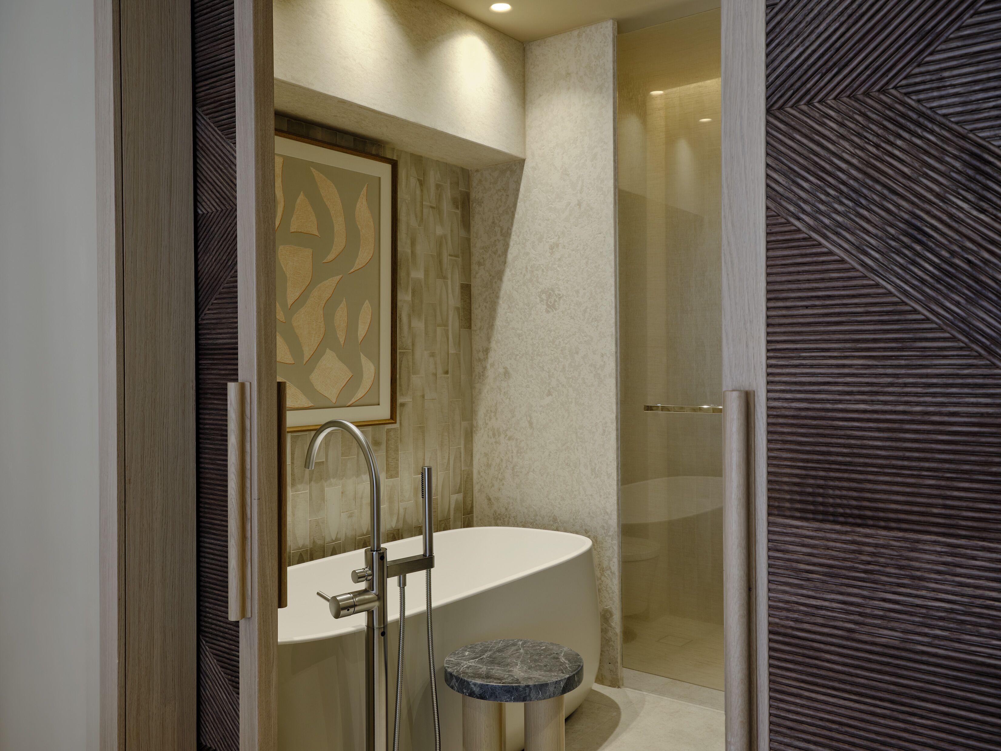 A modern bathroom with a freestanding bathtub, a glass shower enclosure, and a marble countertop.