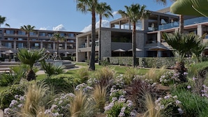 A hotel with multiple floors, outdoor seating areas, and a well-maintained garden with various plants and flowers. - Atlantica Kalliston Resort - Adults Only (Chania)