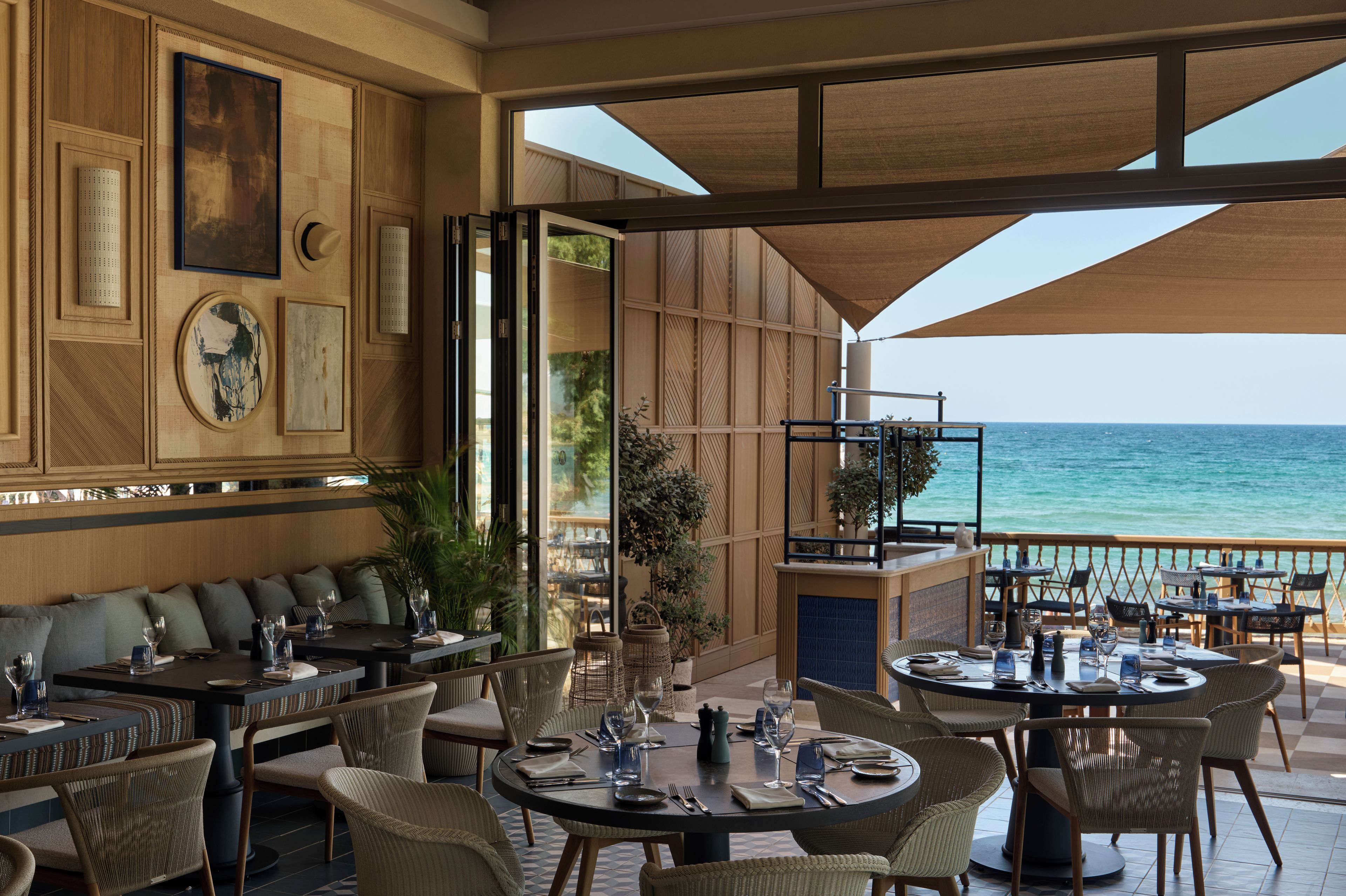An outdoor dining area with tables and chairs, overlooking the sea.
