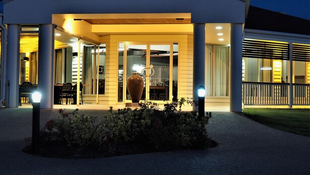 A modern house with a covered entrance, large windows, and a potted plant in the foreground.