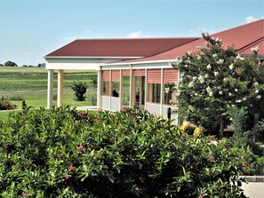 A house with a covered porch, a red roof, and a garden with various plants and flowers.