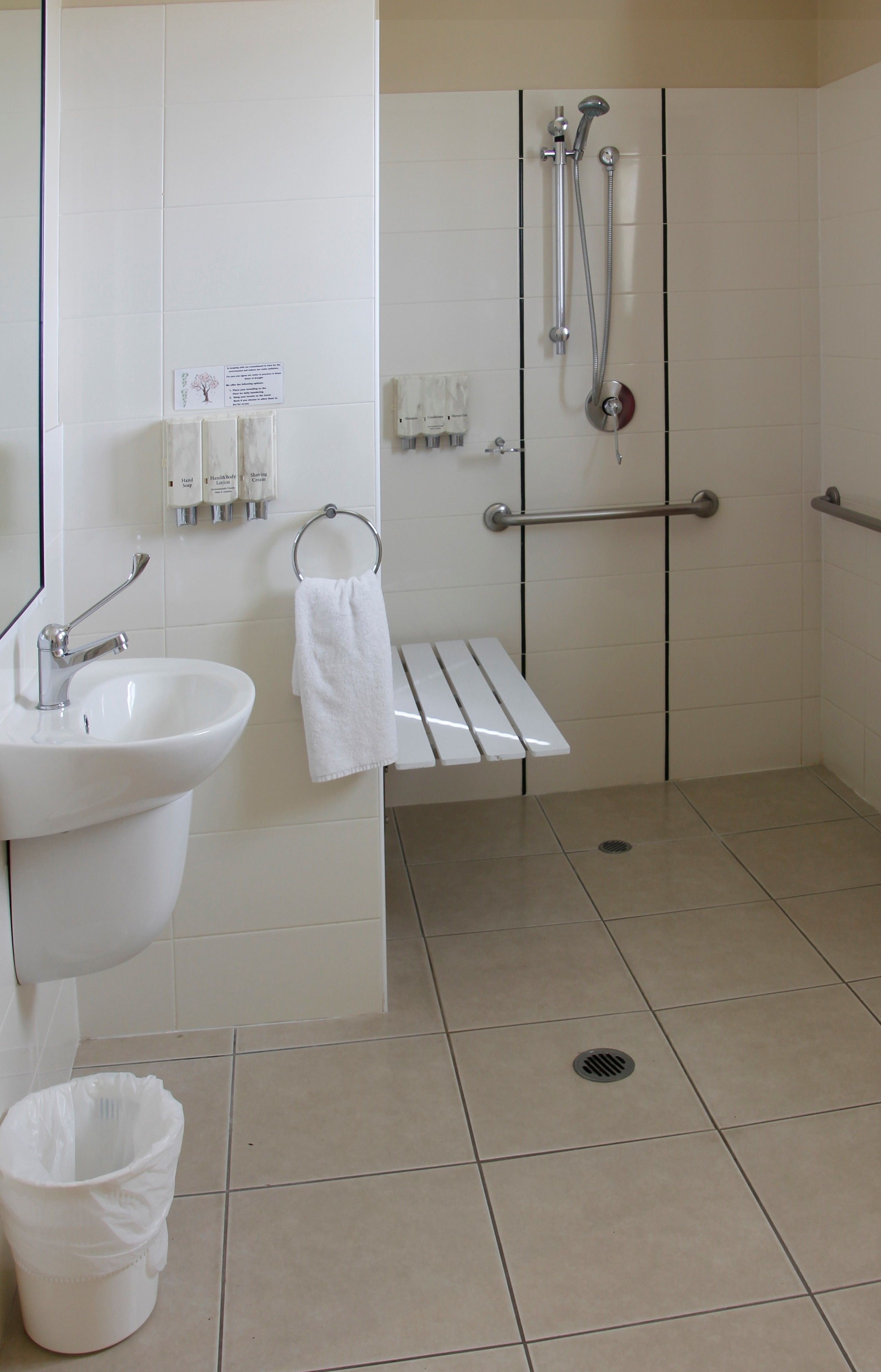 A bathroom with a sink, hand dryer, and a shower stall.