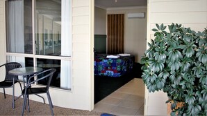 A room with a bed, a window, a chair, and a potted plant.
