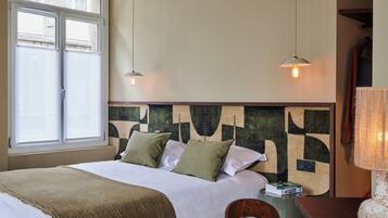 Habitación de hotel con cama, escritorio, lámpara y un cuadro abstracto en la pared.