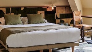 A modern bedroom with a large bed, a wooden headboard, and a small table with chairs. - Hôtel Cartier (Saint-Malo)