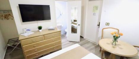 A hotel room with a bed, a dresser, a television, and a dining table with flowers.
