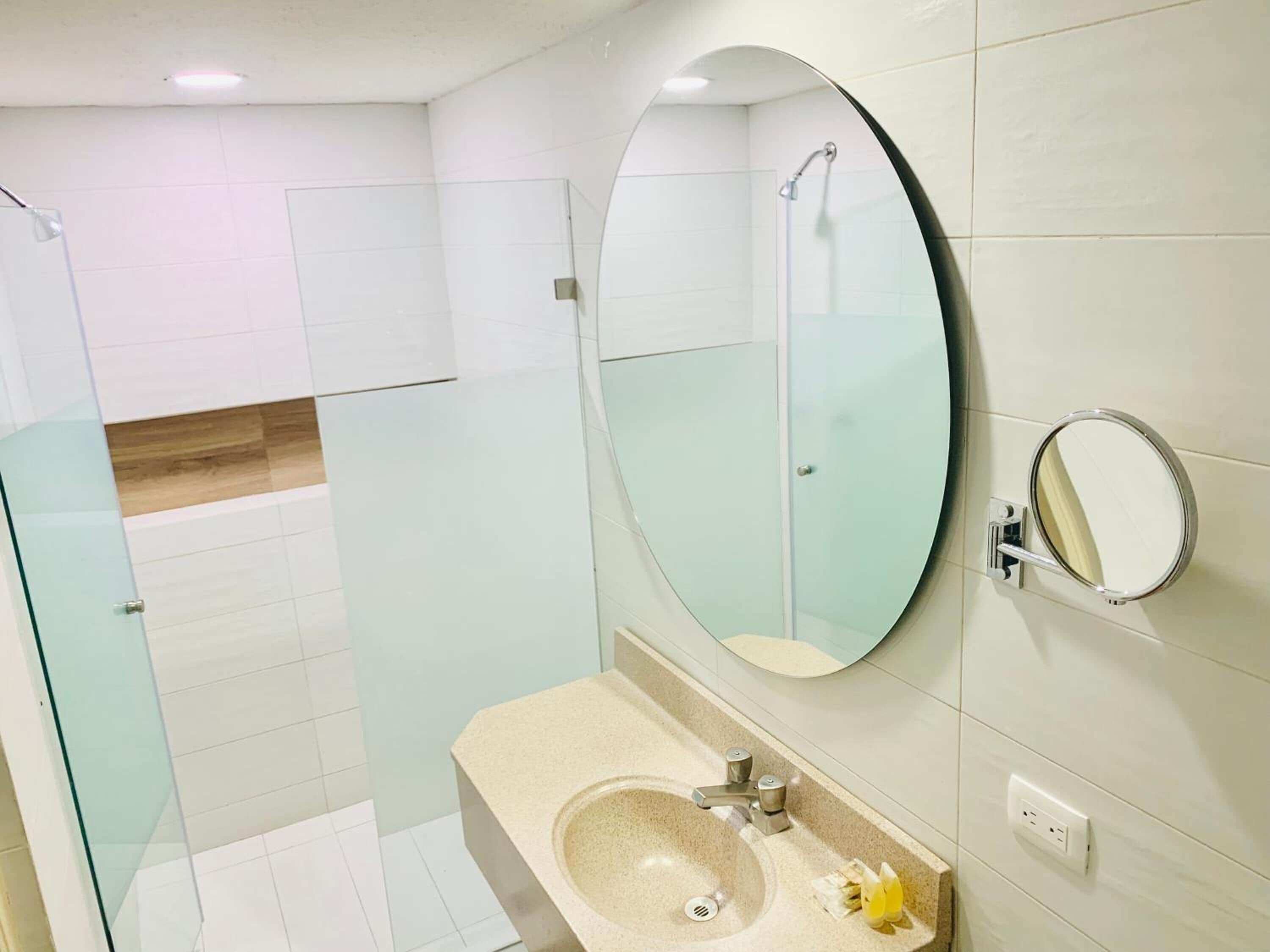 A bathroom with a glass shower enclosure, a sink with a mirror, and a toilet.