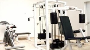 Un gimnasio con diversos equipos de ejercicio, incluyendo un rack para sentadillas, una prensa de banca y máquinas de pesas.